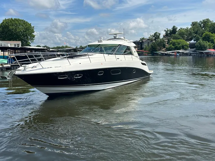  Yacht Photos Pics 2010 Sea Ray 450 Sundancer yacht cruising on a calm lake under a clear sky.