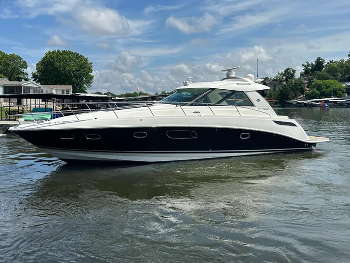  Yacht Photos Pics 2010 Sea Ray 450 Sundancer yacht on a calm lake under a blue sky.