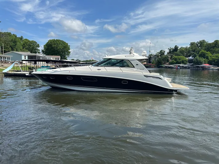  Yacht Photos Pics Sea Ray 450 Sundancer 2010 yacht cruising on a sunny day in a serene lake.