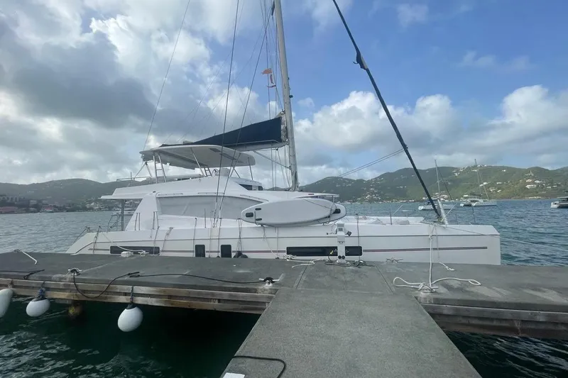  Yacht Photos Pics Leopard 58 catamaran docked at marina, scenic mountain backdrop, cloudy sky.