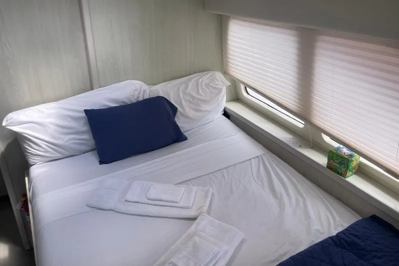  Yacht Photos Pics Cozy bed in Leopard 58 yacht cabin, featuring white linens and blue pillow.