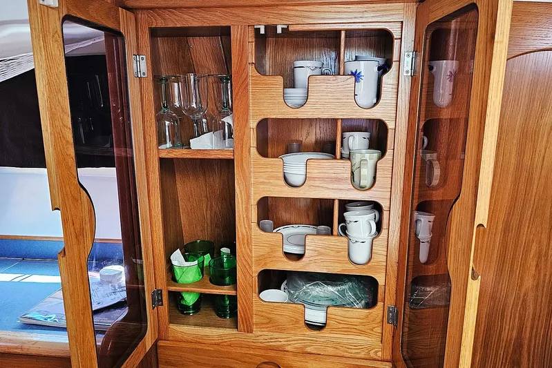 Zephyros Yacht Photos Pics Wooden cabinet with glassware and mugs in a 2009 Seawind 36XL yacht interior.