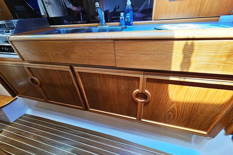 Zephyros Yacht Photos Pics Wooden kitchen cabinetry on a 2009 Seawind 36XL yacht, featuring a sink and cleaning supplies.