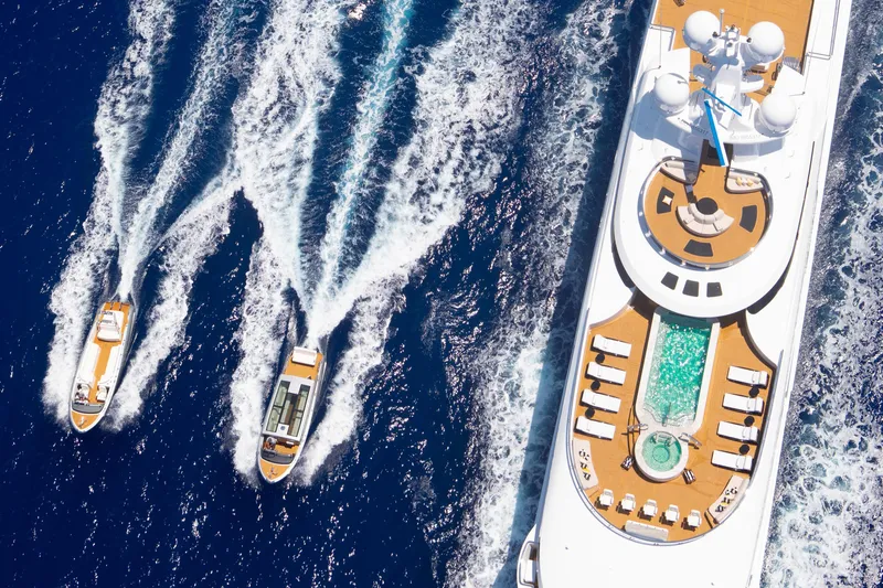 Boardwalk Yacht Photos Pics Aerial view of luxurious 2021 Feadship yacht with pool, accompanied by two smaller boats.