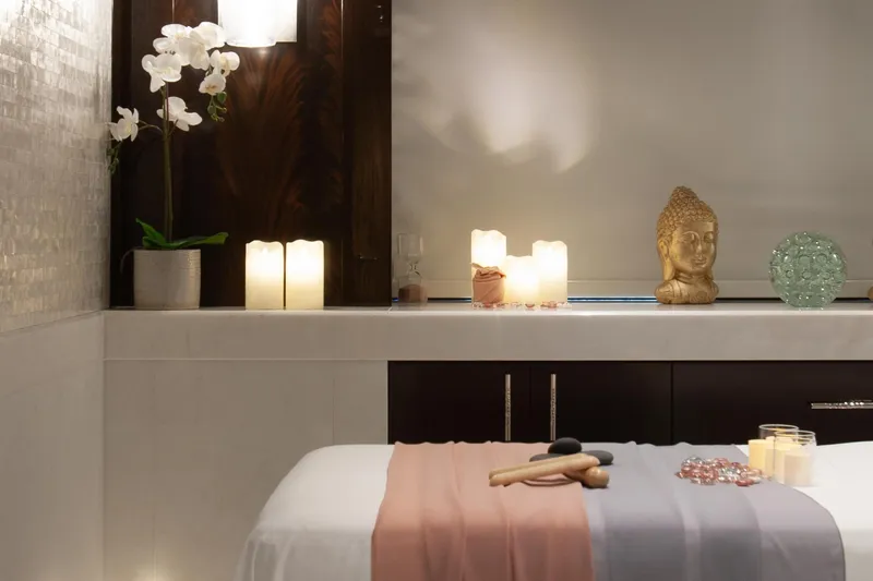 Boardwalk Yacht Photos Pics Luxurious spa room on Feadship Costum yacht, featuring candles, orchids, and a Buddha statue.