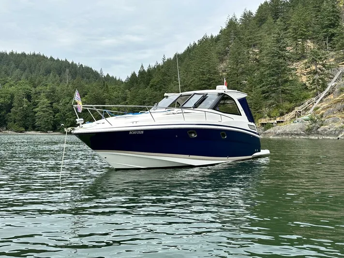  Yacht Photos Pics 2014 Regal Sport Coupe boat anchored on a serene lake with forested hills.
