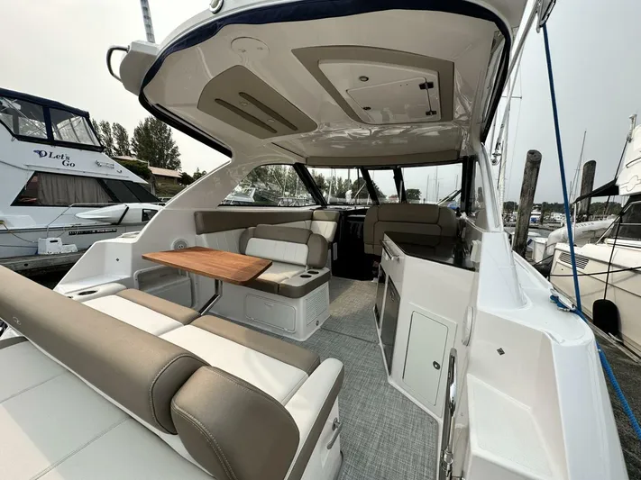  Yacht Photos Pics 2014 Regal Sport Coupe interior with beige seating and wooden table, docked at marina.