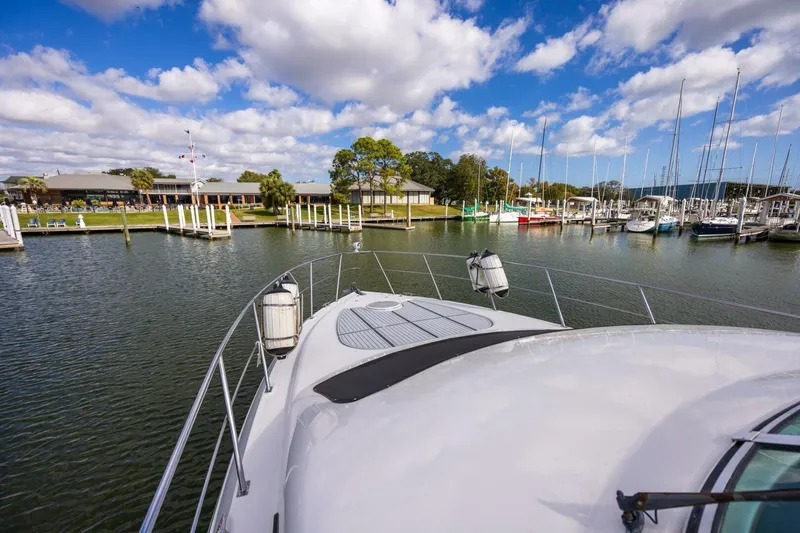 Sky Brown Yacht Photos Pics 2005 Cruisers Yachts 455 Express Motoryacht docked at a scenic marina under blue skies.