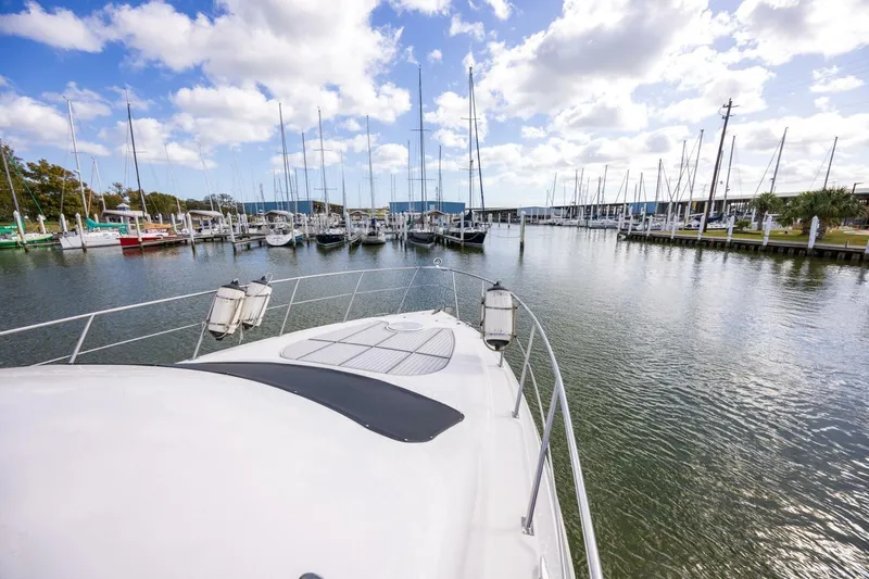 Sky Brown Yacht Photos Pics 2005 Cruisers Yachts 455 Express Motoryacht docked in a marina under a partly cloudy sky.
