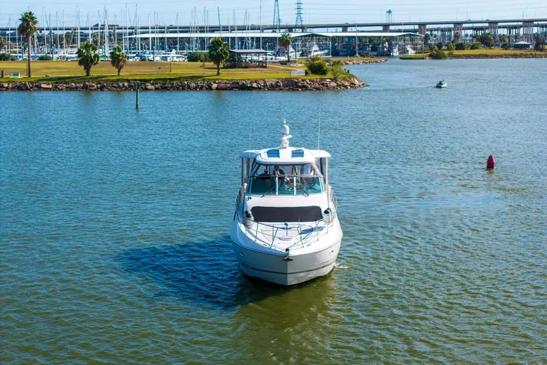 Sky Brown Yacht Photos Pics 2005 Cruisers Yachts 455 Express Motoryacht on calm water near marina.