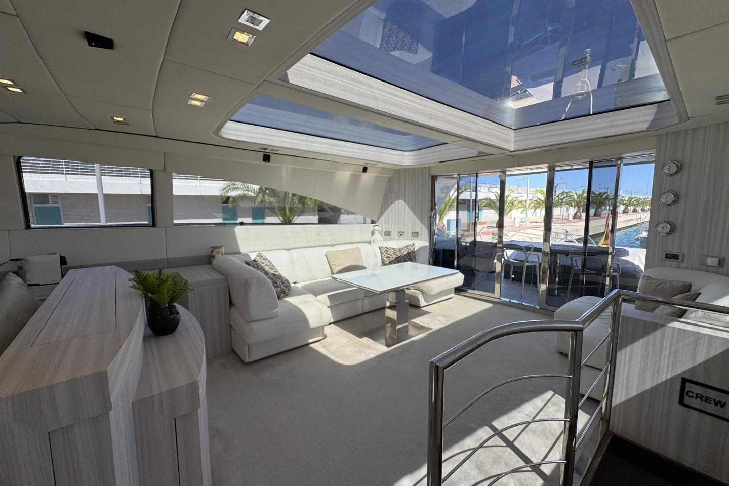Luxurious yacht interior with skylight, modern furnishings, and marina view. AB 78, 2007 model.