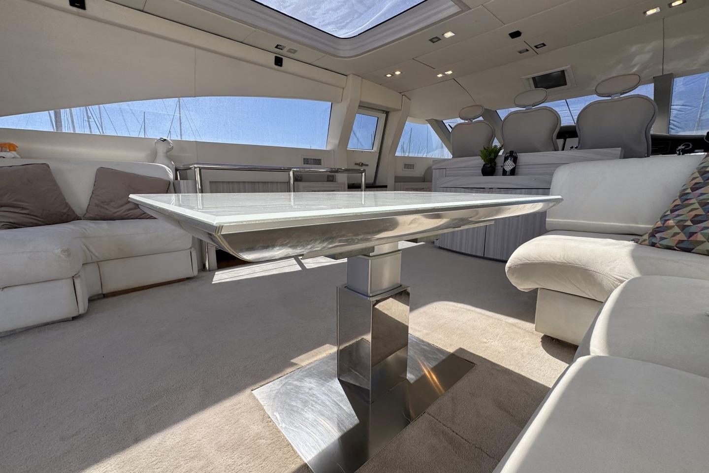 Luxurious yacht interior with modern furnishings, featuring a sleek glass table and plush seating.