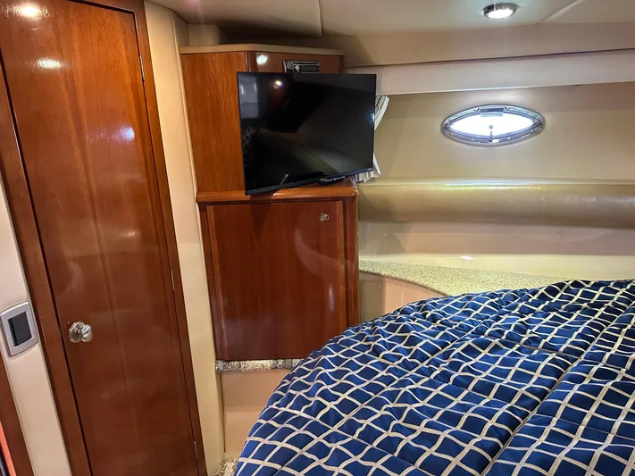 Vrpro Yacht Photos Pics 2007 Meridian 411 Sedan cabin with TV, wooden cabinetry, and blue checkered bedding.
