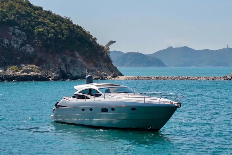  Yacht Photos Pics 2007 Pershing 50 yacht cruising in clear blue waters near rocky coastline.