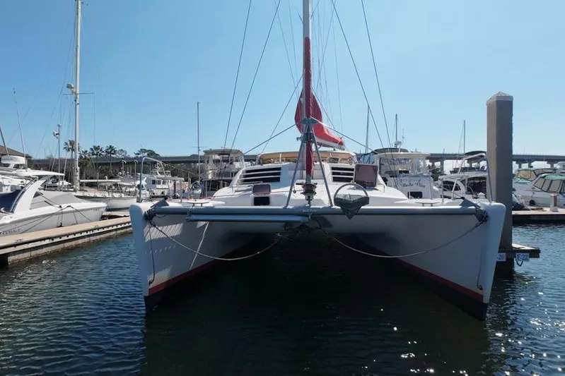 Next Of Kin Yacht Photos Pics 2000 Leopard 38 catamaran docked in marina, front view with red sail.