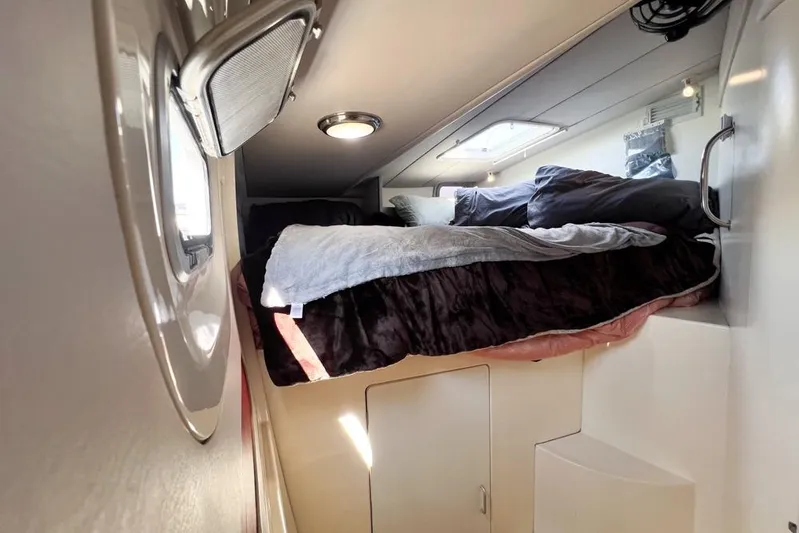 Next Of Kin Yacht Photos Pics Cozy cabin interior of 2000 Leopard 38 catamaran with bed and porthole window.