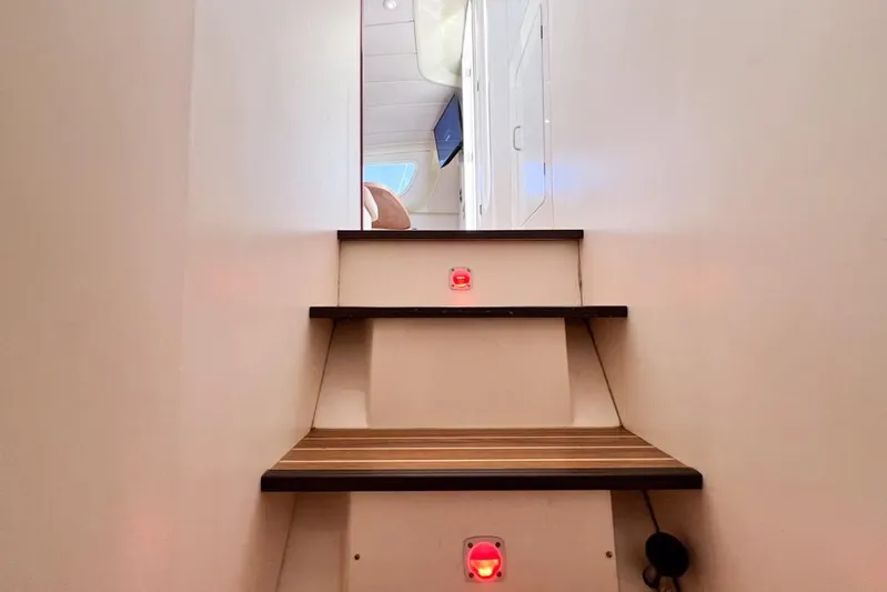 Next Of Kin Yacht Photos Pics Staircase inside 2000 Leopard 38 yacht, featuring wooden steps and red lights.