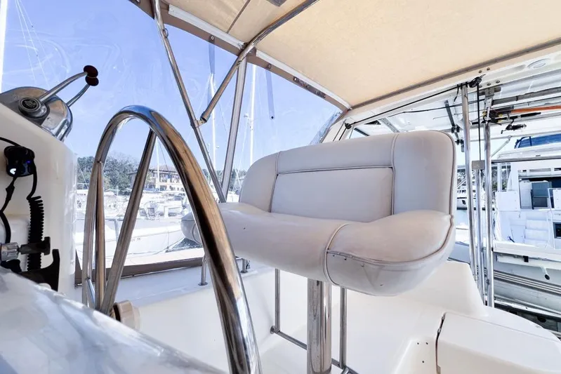 Next Of Kin Yacht Photos Pics Helm station of 2000 Leopard 38 catamaran with steering wheel and cushioned seat.