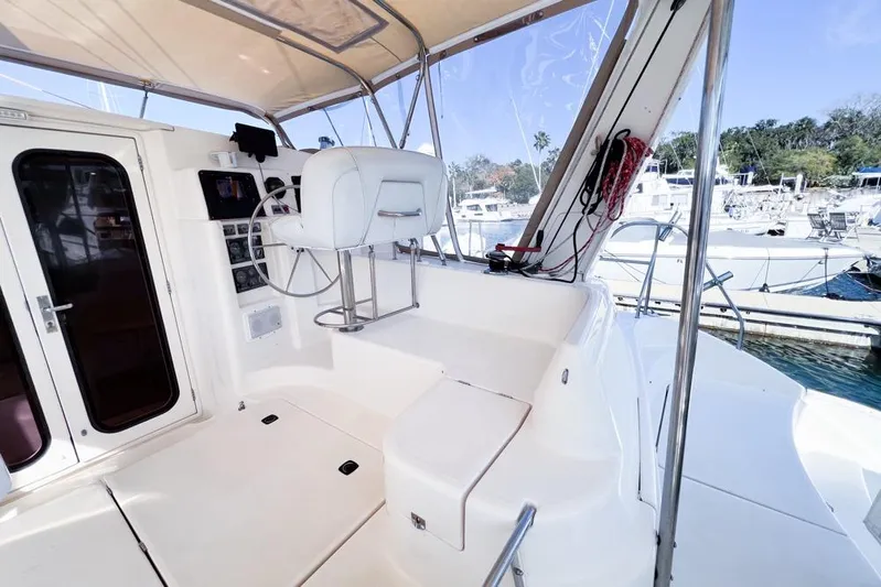 Next Of Kin Yacht Photos Pics Helm station of 2000 Leopard 38 catamaran with white seating and marina view.