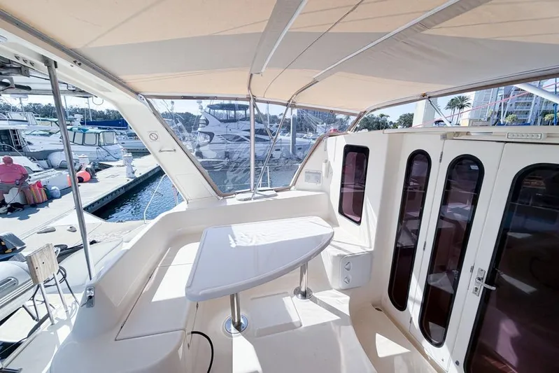 Next Of Kin Yacht Photos Pics Leopard 38 catamaran cockpit with table, docked at marina, sunny day.