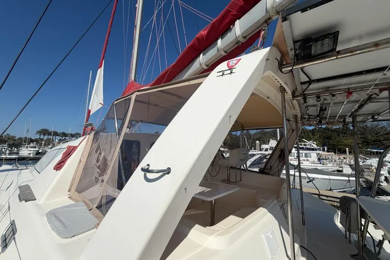 Next Of Kin Yacht Photos Pics 2000 Leopard 38 catamaran with red sails docked at a marina under clear blue skies.