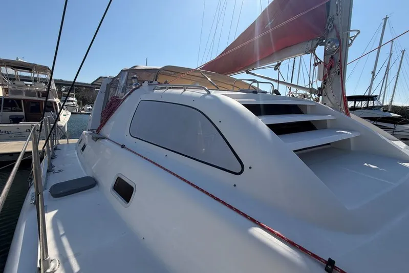 Next Of Kin Yacht Photos Pics 2000 Leopard 38 catamaran with red sail, docked in marina under clear sky.