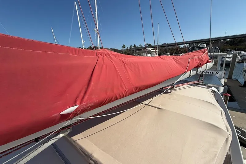 Next Of Kin Yacht Photos Pics Red sail cover on Leopard 38 catamaran, docked in marina, clear blue sky.