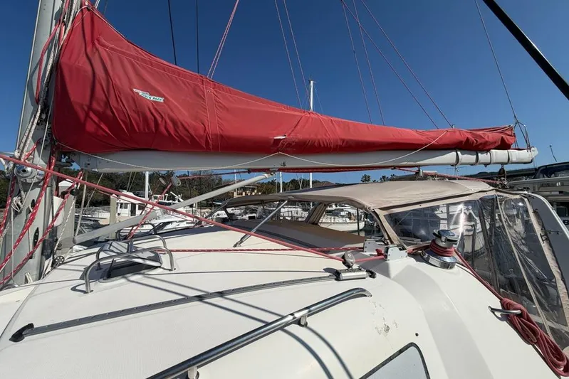 Next Of Kin Yacht Photos Pics Sailboat with red sail cover, Leopard 38 model, 2000, docked in marina under clear sky.