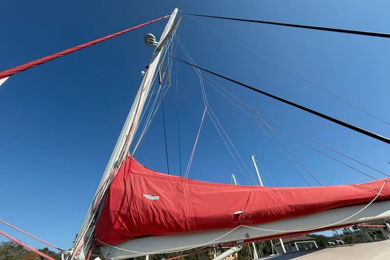 Next Of Kin Yacht Photos Pics Sailboat with red sail cover, Leopard 38 model, 2000, against clear blue sky.