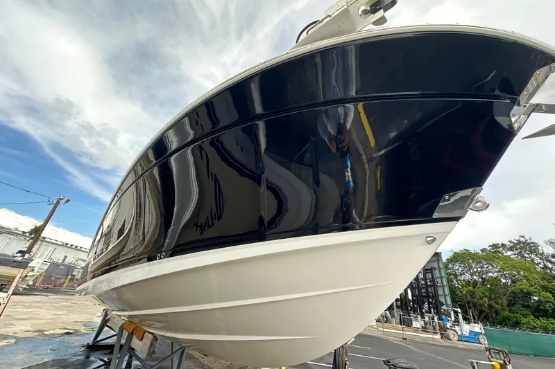  Yacht Photos Pics 2021 Blackfin 332 CC boat with sleek black hull, docked outdoors.