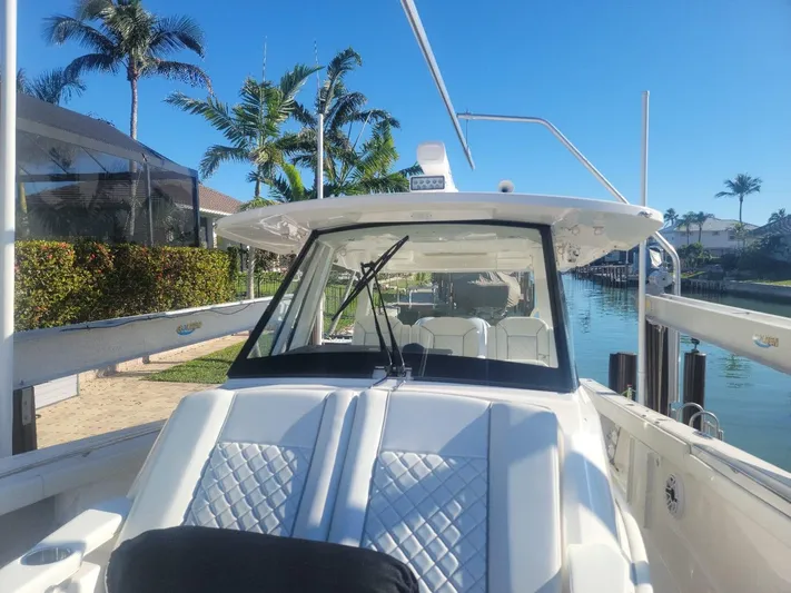  Yacht Photos Pics 2021 Pursuit S 378 Sport boat docked by palm trees and waterway.
