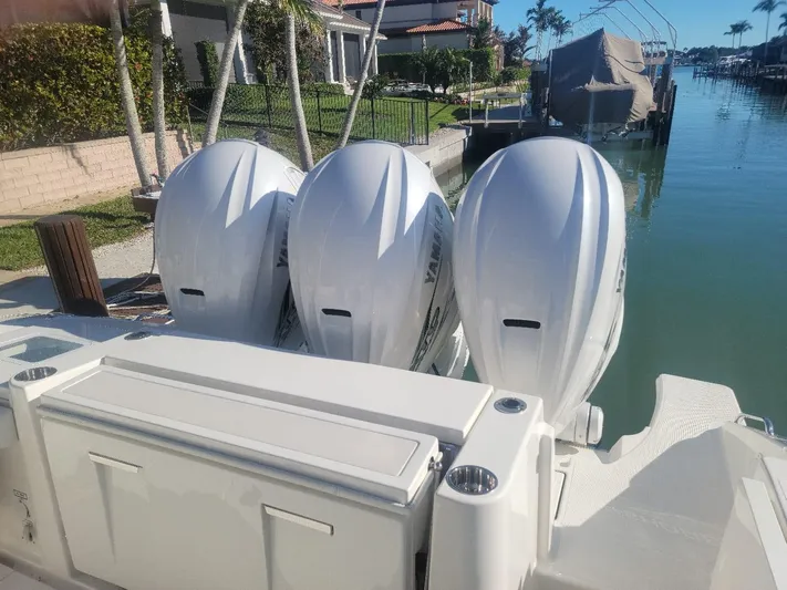  Yacht Photos Pics 2021 Pursuit S 378 Sport boat with triple outboard engines docked by waterfront homes.