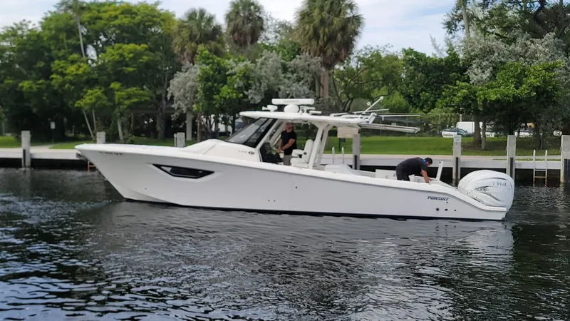  Yacht Photos Pics 2021 Pursuit S 378 Sport boat on a calm river near a lush, green shoreline.