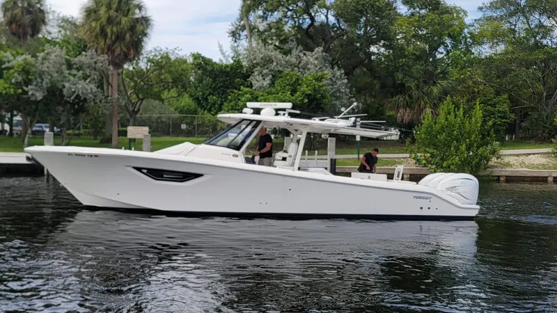  Yacht Photos Pics 2021 Pursuit S 378 Sport boat cruising on a calm river with lush greenery.