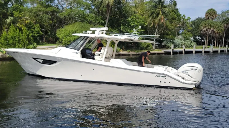  Yacht Photos Pics 2021 Pursuit S 378 Sport boat cruising on a calm river with lush greenery.