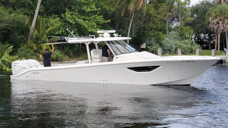  Yacht Photos Pics 2021 Pursuit S 378 Sport boat cruising on a calm river, surrounded by lush greenery.
