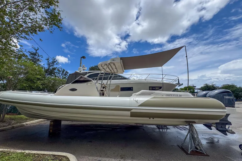  Yacht Photos Pics 2023 Tender Impertus 36 boat with canopy, parked outdoors under a cloudy sky.