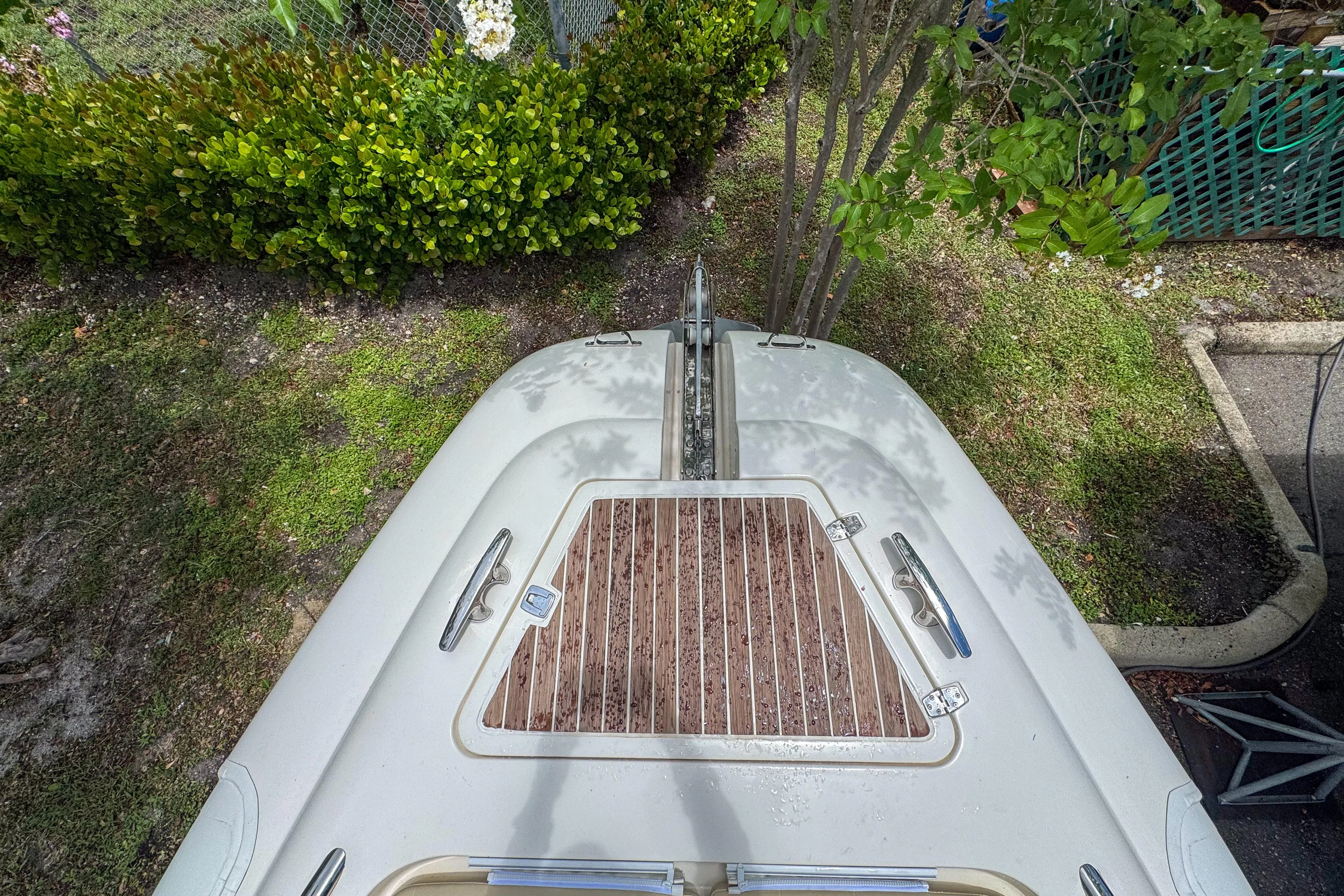  Yacht Photos Pics Top view of 2023 Tender Impertus 36 boat with wooden deck, surrounded by greenery.