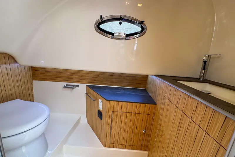  Yacht Photos Pics Modern bathroom interior of 2023 Tender Impertus 36 yacht with wood accents and porthole.