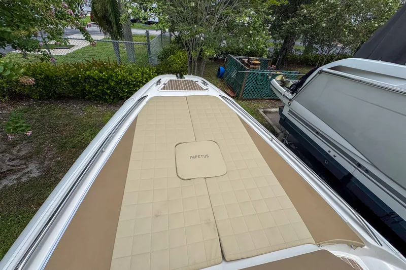  Yacht Photos Pics 2023 Tender Impertus 36 boat deck with tan cushioned seating, surrounded by greenery.