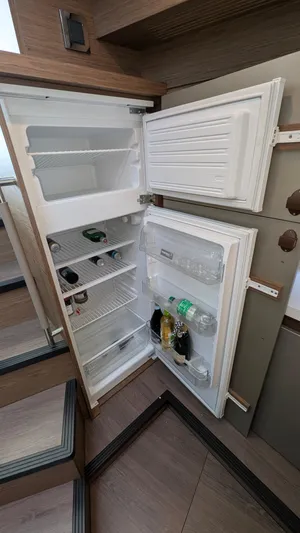 Best Life Yacht Photos Pics Open refrigerator inside 2019 Beneteau GT 46 yacht, showing stocked shelves and modern interior design.
