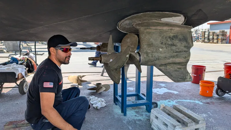 Best Life Yacht Photos Pics Man inspecting propeller of 2019 Beneteau GT 46 yacht in a shipyard.