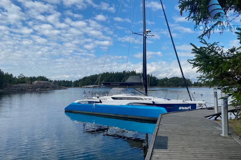  Yacht Photos Pics 2021 Dragonfly 40 sailboat docked on a serene lake with cloudy sky.