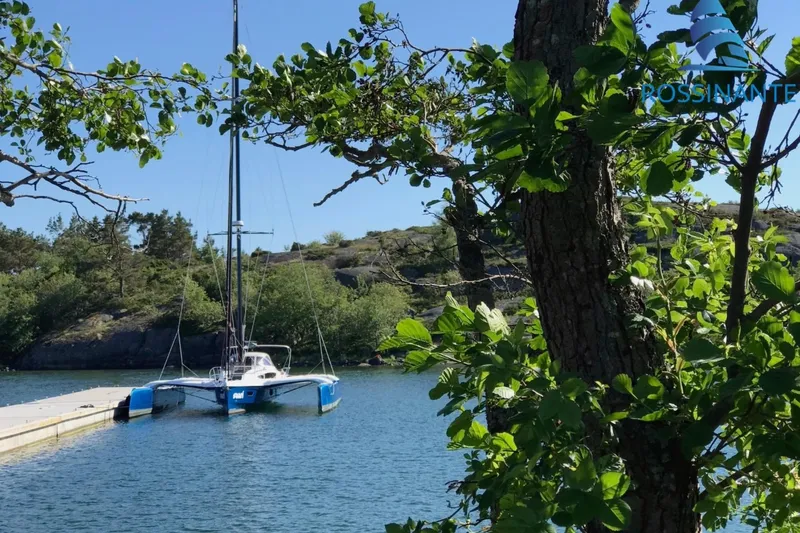  Yacht Photos Pics Sailboat Dragonfly 40, 2021 model, docked in a scenic, tree-lined harbor.