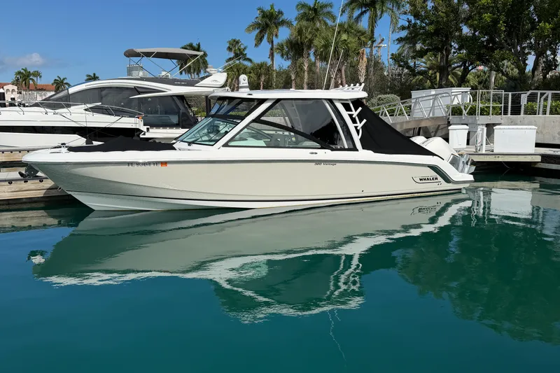 Yacht Photos Pics 2022 Boston Whaler 320 Vantage boat docked in a marina with palm trees.