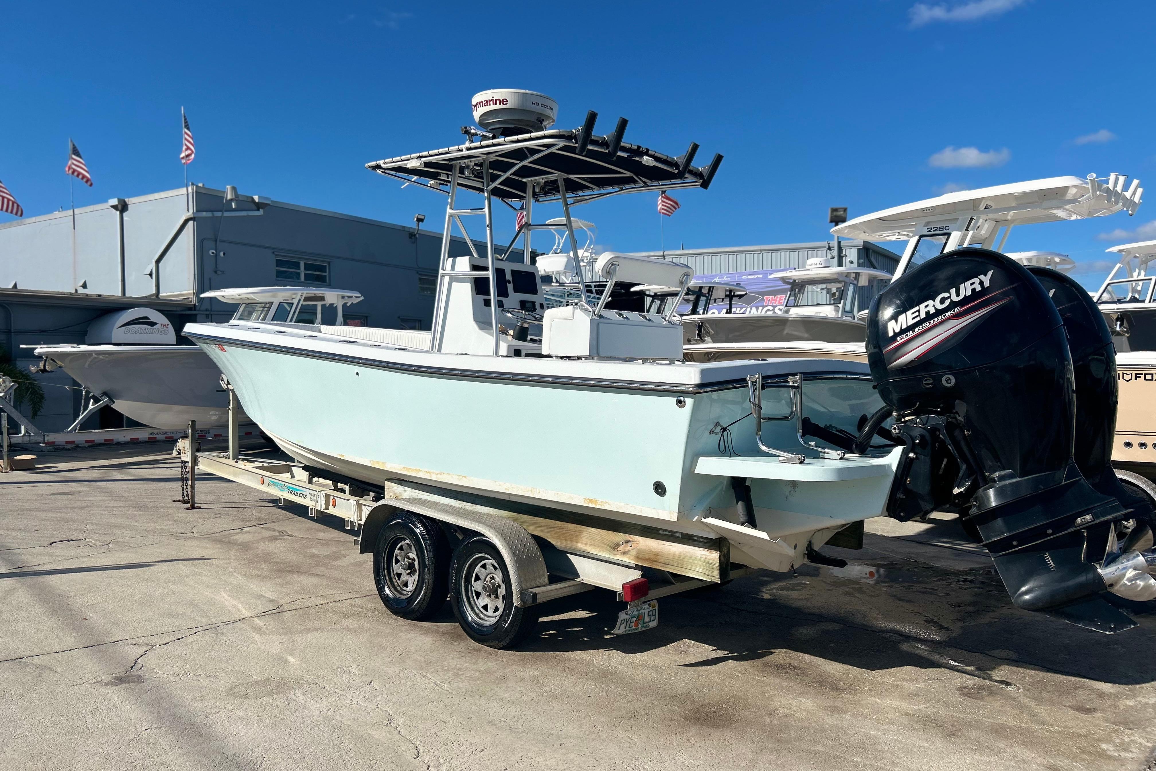 1991 Contender 25 Open boat on trailer with Mercury outboard motor, docked outdoors.