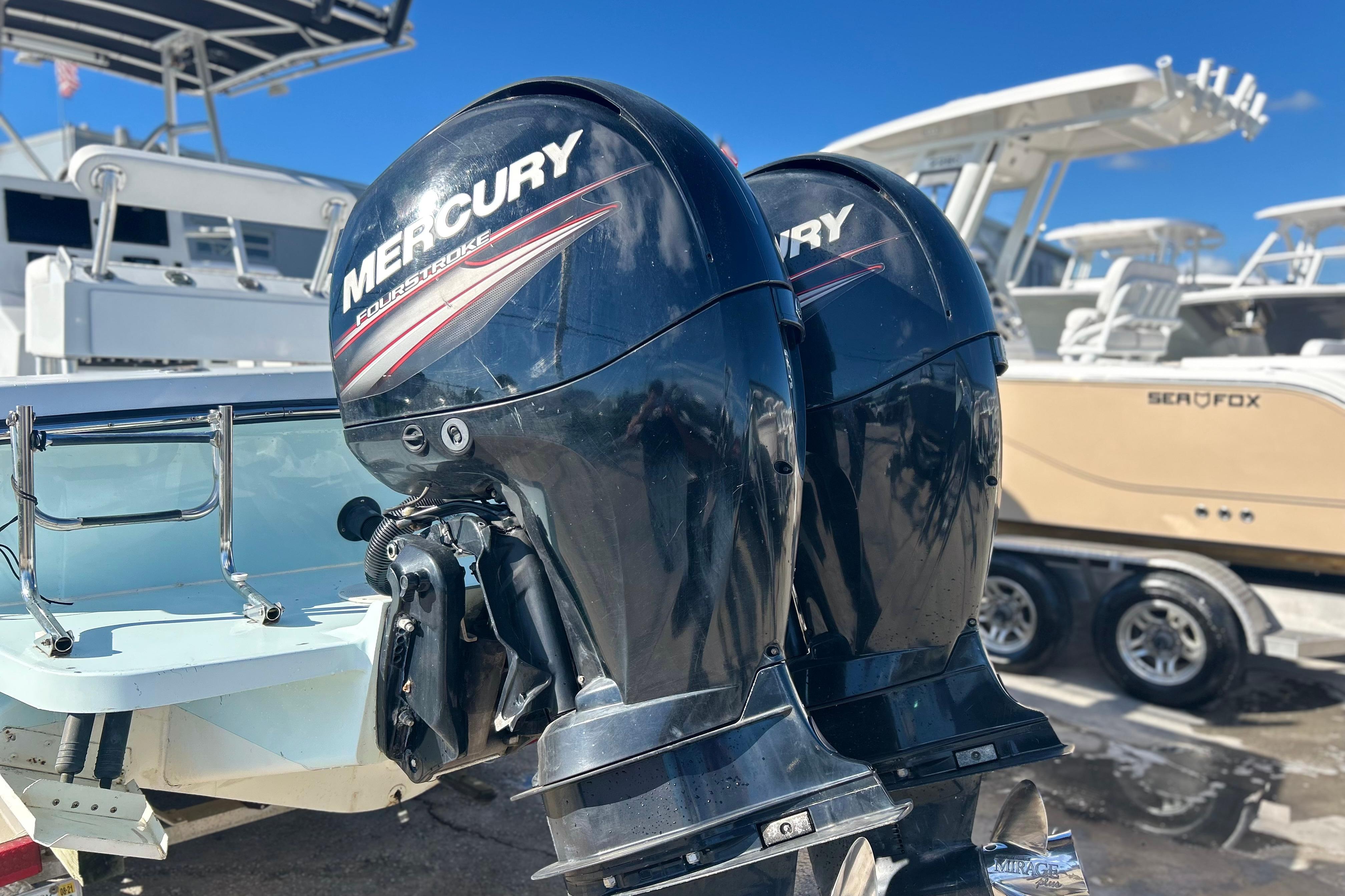 Twin Mercury outboard engines on a 1991 Contender 25 Open boat, docked with other vessels.