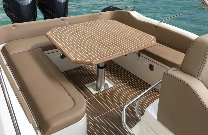 Stock Inventory Yacht Photos Pics 2024 Nuova Jolly Prince 38 boat interior with cushioned seating and wooden table.