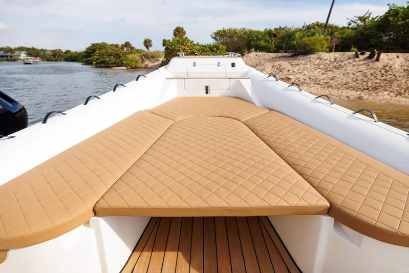 Stock Inventory Yacht Photos Pics 2024 Nuova Jolly Prince 38 boat with tan cushioned deck, docked by sandy shore.