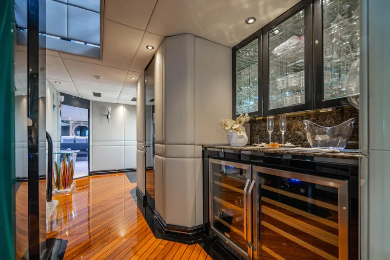 Quantum Yacht Photos Pics Luxurious interior of 1989 Broward Tri-Deck yacht with polished wood floors and modern bar area.